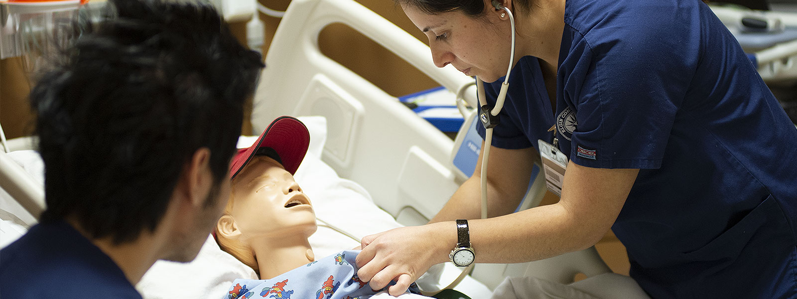 Close-up of nursing student practicing vitals on a manikin.